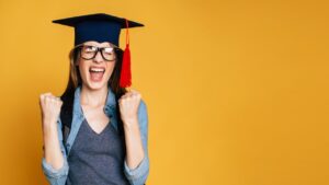 ACT Preparation: cheerful graduate wearing a mortarboard cap celebrating success against a vibrant yellow background.